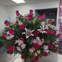 Basket arrangement of hot pink roses, pink lilies, and pale pink flowers