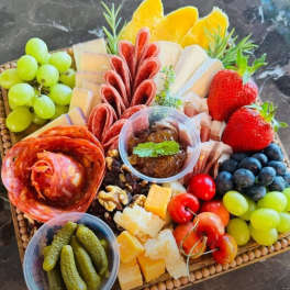 Charcuterie board with meats, cheeses, fruit, olives, and crackers