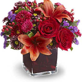 Red roses and orange lilies in a square glass vase