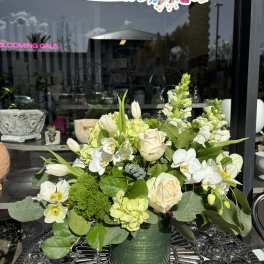 White and pale green floral arrangement in a green vase