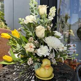 Bouquet of white flowers and yellow tulips in a yellow duck vase