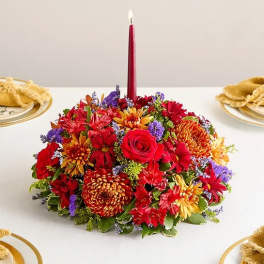 Low floral centerpiece with a red taper candle in the middle