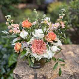 Mixed bouquet of peach, white, and pink flowers in a glass vase