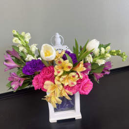 Colorful bouquet in a white lantern vase with pink, purple, yellow, and white flowers