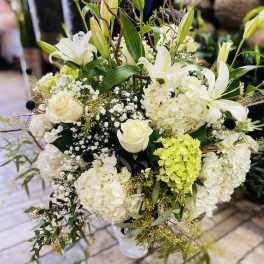 White lilies and roses arranged with hydrangeas in a vase