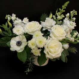 White floral arrangement with roses and anemone in a low vase