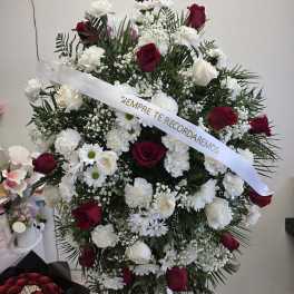 Standing funeral spray of red and white flowers with a memorial ribbon