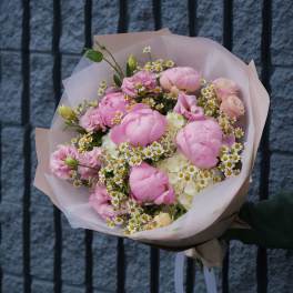 Pink bouquet with white daisy-like flowers wrapped in pale paper
