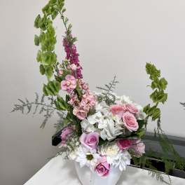 Pink roses and white hydrangeas in a white vase with tall green accents