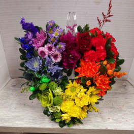 Heart-shaped bouquet of multicolored flowers with a clear vase in the center