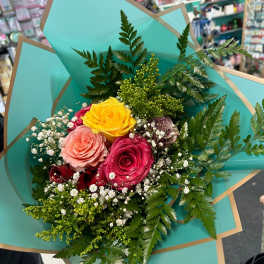 Bouquet of multicolored roses wrapped in turquoise paper