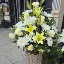 Tall white and pale yellow floral arrangement in a decorative pedestal vase