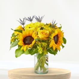 Sunflower and yellow rose bouquet in a clear glass vase