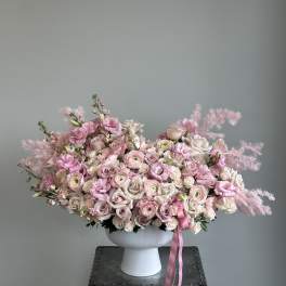 Large pink and white floral arrangement in a white pedestal vase