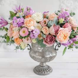 Pastel bouquet of roses and mixed blooms in a silver urn vase