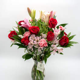 Bouquet of red roses, pink lilies, and carnations in a glass vase