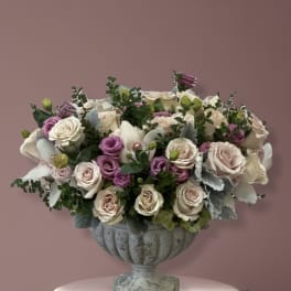 Pink and white roses arranged in a gray urn vase