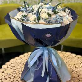 Bouquet of white roses and blue flowers wrapped in navy and white paper
