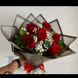 Bouquet of red roses with white baby's breath in dark wrap
