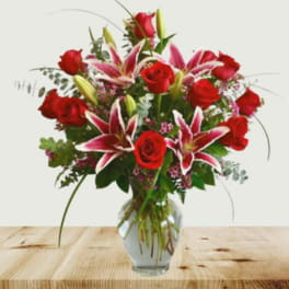 Bouquet of red roses and pink lilies in a clear glass vase
