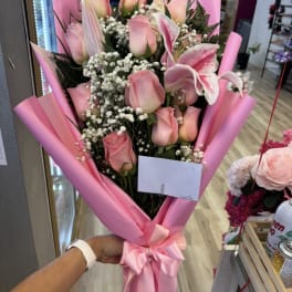 Pink roses and lilies in pink wrap with a satin bow