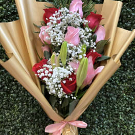 Bouquet of pink and red roses with white baby's breath in gold wrap