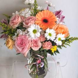 Mixed bouquet of pink roses, white daisies, and an orange gerbera daisy in a clear glass vase