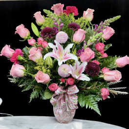Pink roses and lilies in a decorative vase with a ribbon