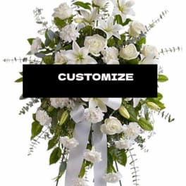 White floral standing spray with lilies and roses on a ribboned easel