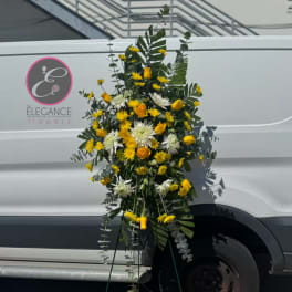 Tall standing floral spray with yellow and white blooms on a metal easel