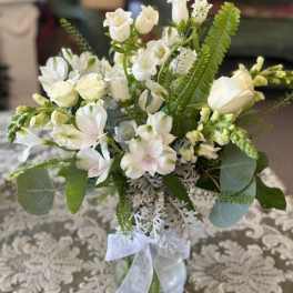 White floral bouquet in a glass vase with a ribbon