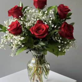 Red roses and baby's breath arranged in a clear glass vase