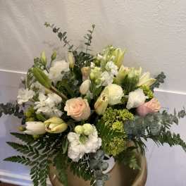 Mixed bouquet of white and pale peach flowers in a gold vase