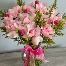 Pink rose bouquet in a glass vase with a bright ribbon