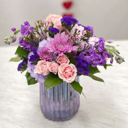Pink and purple mixed bouquet in a ribbed glass vase