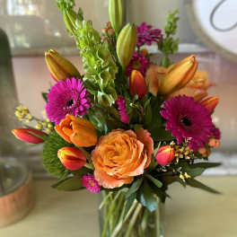 Colorful bouquet of tulips, roses, and gerbera daisies in a glass vase