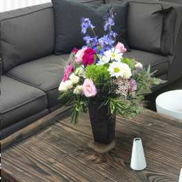 Mixed bouquet in a black vase with pink, white, and blue flowers