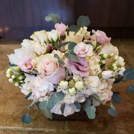 Soft pink and white bouquet with roses and eucalyptus in a low container