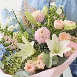 Pastel bouquet with lilies, roses, and pink blooms wrapped in pink paper