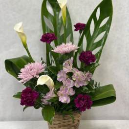 Basket arrangement with pink and purple flowers and white calla lilies