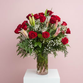 Red roses and lilies arranged in a clear glass vase