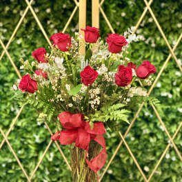 Red roses arranged in a clear glass vase with a red ribbon