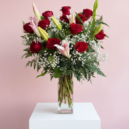Red roses and lilies in a tall glass vase