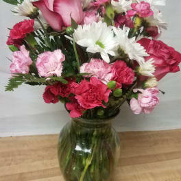 Pink roses, carnations, and white daisies in a glass vase