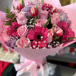 Pink bouquet with roses, gerbera daisies, and tulips wrapped in pastel paper