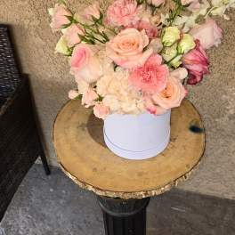Pink and peach floral arrangement in a white round box