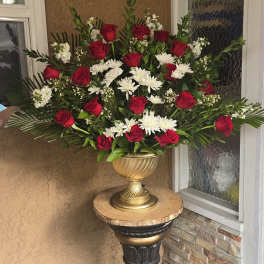Red roses and white daisies in a gold urn on a pedestal