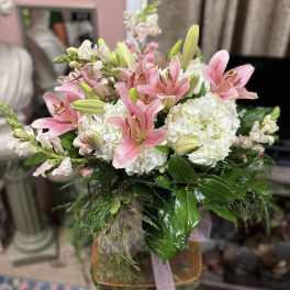 Pink lilies and white hydrangeas arranged in a glass vase