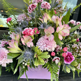 Pink and lavender mixed flower arrangement in a lavender container