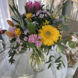 Mixed bouquet in a clear glass vase with yellow and pink blooms